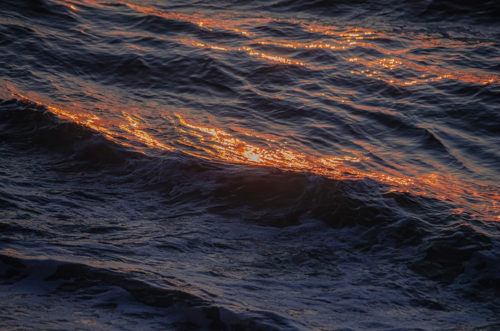 Orange light streaks across dark ocean waves.